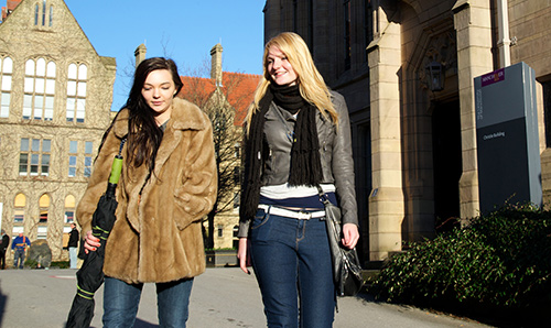 Two female students walking and talking on campus
