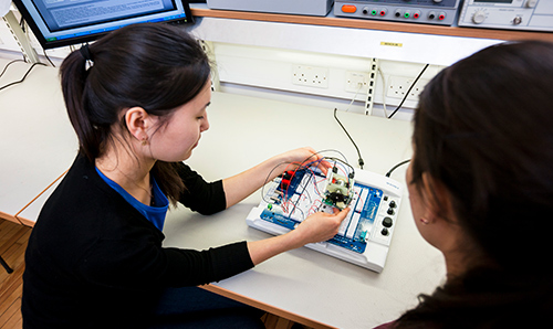Two female researchers operating wires and electrical equipment