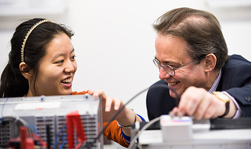 Employer and student smiling while adjusting some machinery