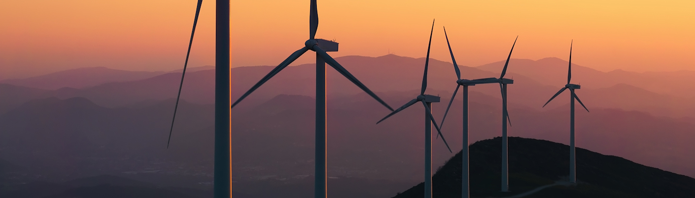 A series of wind turbines against a sunset