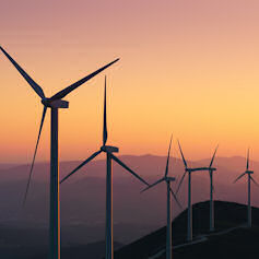 A series of wind turbines against a sunset