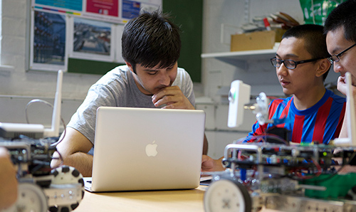 Three students discussing project around laptop