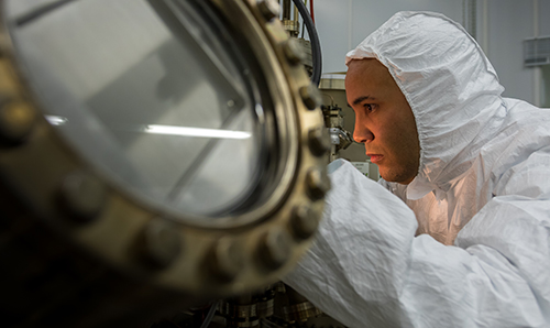 A researcher operating a molecular beam epitaxy